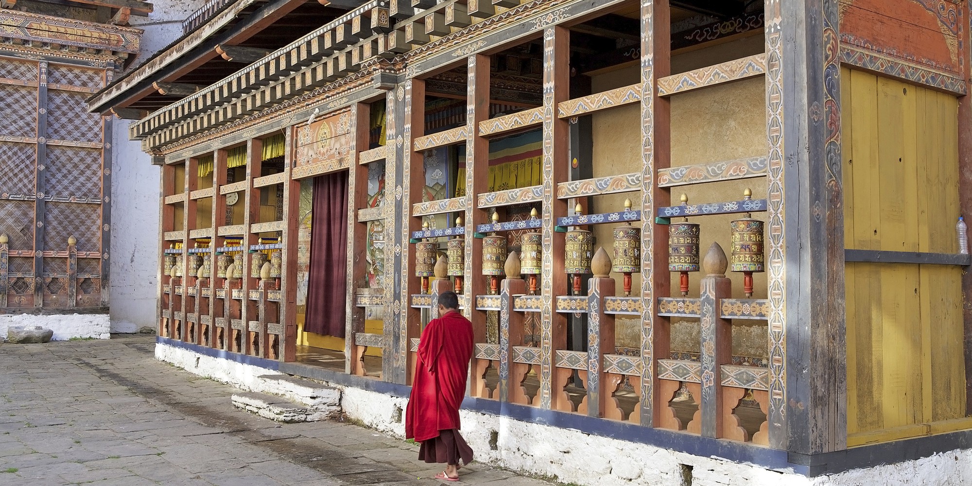 Prayer wheels and buddhist monk at the Trongsa Dzong, Trongsa, Bhutan. Trongsa Dzong is the largest dzong fortress in Bhutan. A temple was first established at the location in 1543 by the Drukpa Lama Ngagi Wangchuk. In 1647 his great-grandson Shabdrung Ngawang Namgyal constructed the first dzong to replace it.